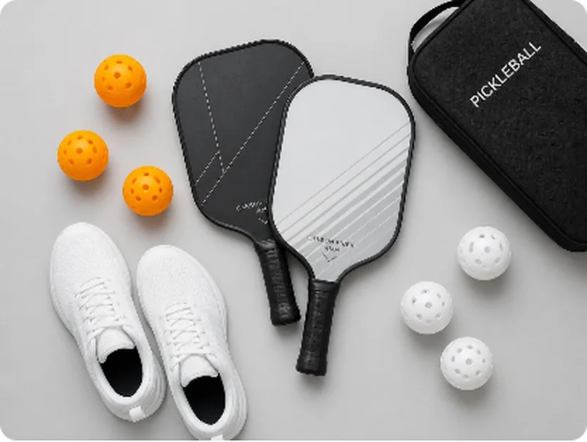 Dos palas, pelotas, calzado y una funda de pickleball sobre fondo gris